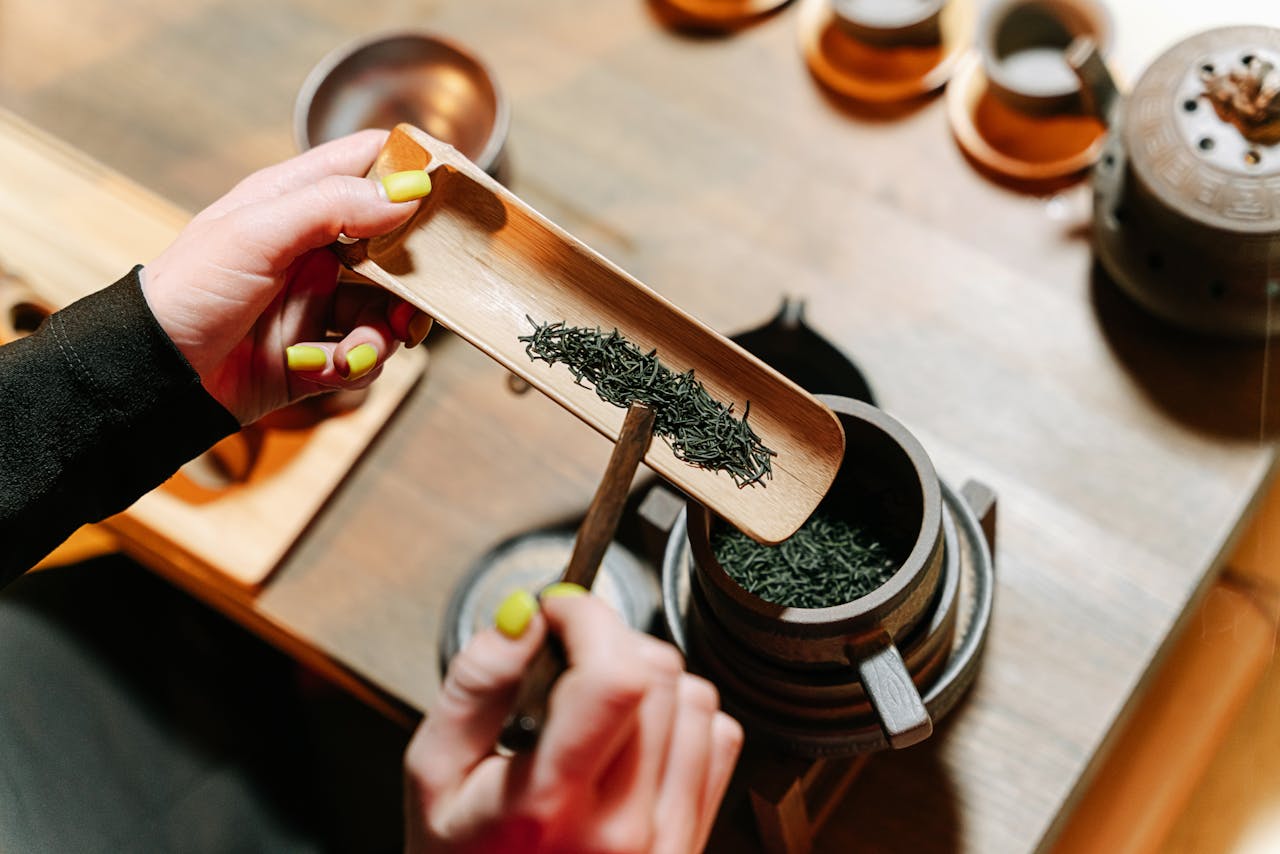 about-04 Close-up of hands preparing green tea leaves for a traditional tea ceremony indoors.